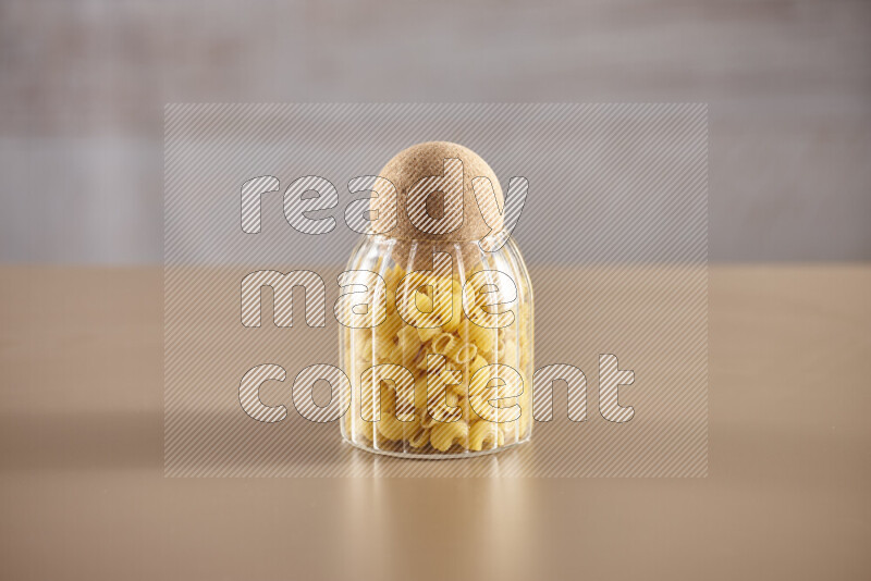 Raw pasta in glass jars on beige background