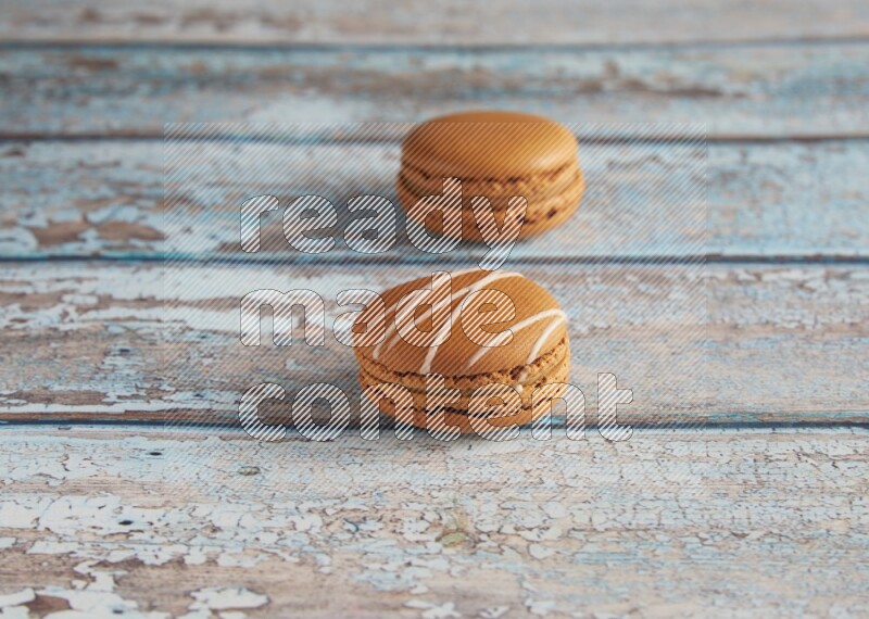 45º Shot of of two assorted Brown Irish Cream, and Brown Maple Taffy macarons  on light blue background