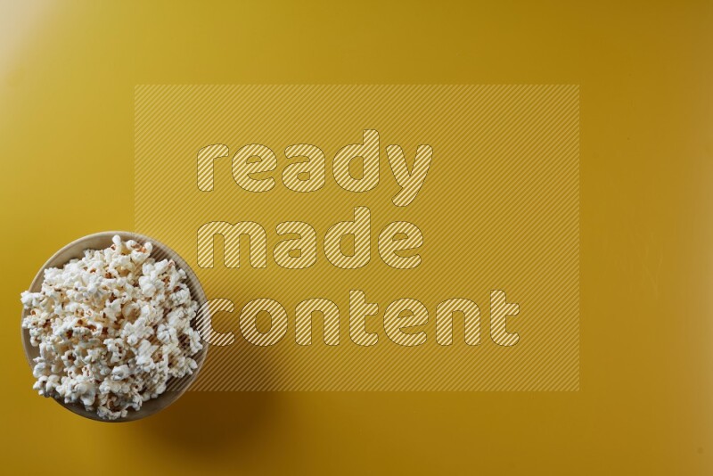 A multicolored ceramic plate full of popcorn on a yellow background in different angles