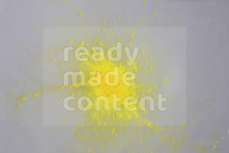 The image captures a dramatic splatter of yellow paint over a white backdrop