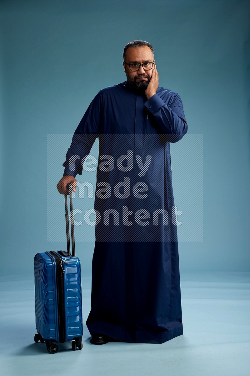 Saudi Man without shimag Standing pulling travel bag on blue background