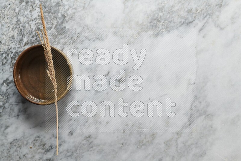 Wheat stalks on multicolored pottery oven plate on grey marble background