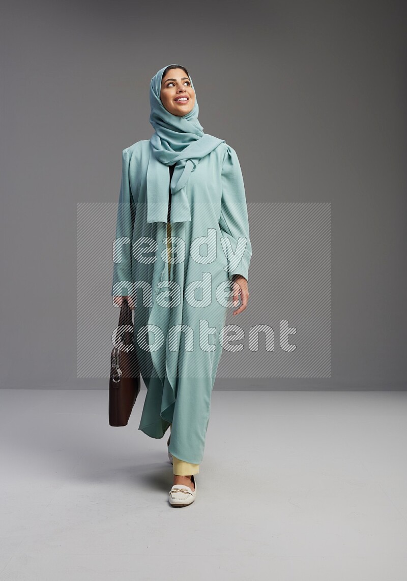 Saudi Woman wearing Abaya standing holding bag on Gray background