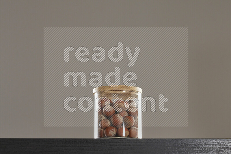 Hazelnuts in a glass jar on black background