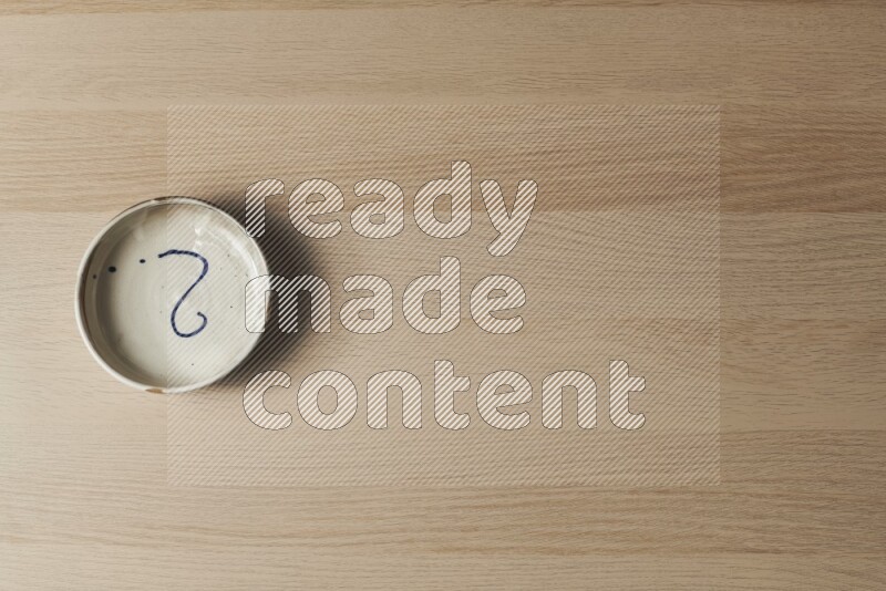 وعاء فخاري متعدد الألوان على خلفية خشبية فاتحة