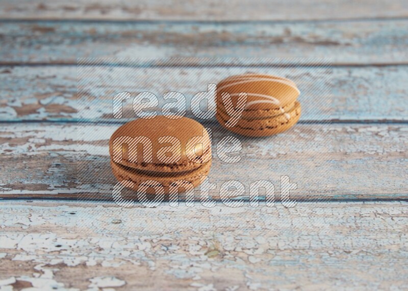 45º Shot of of two assorted Brown Irish Cream, and Brown Coffee macarons on light blue background