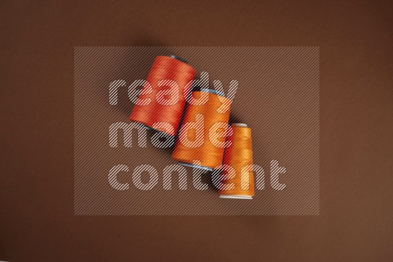 Orange sewing supplies on brown background