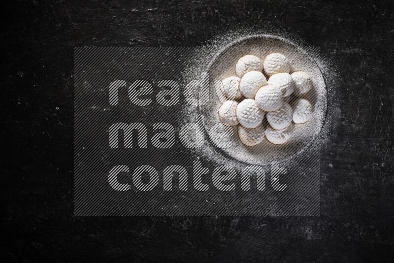 Kahk on a serving plate on a black background