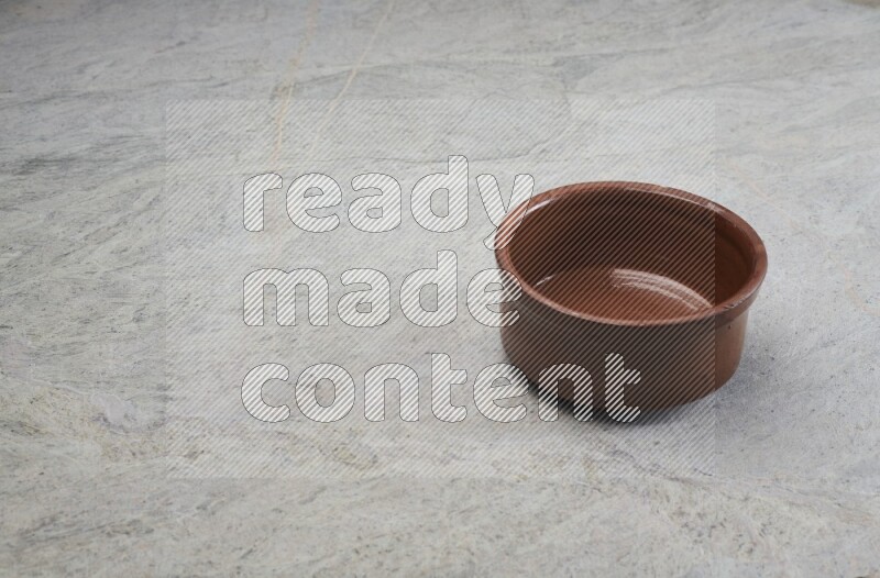 A brown pottery bowl on grey marble background