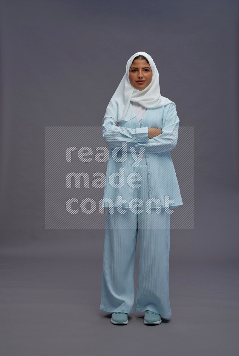 Saudi woman wearing hijab clothes standing with crossed arms on gray background