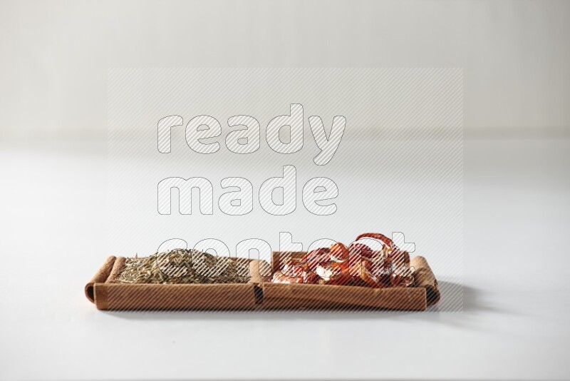 مربعان من أعواد القرفة ممتلئان بالفلفل الحار المجفف وحبوب الكمون علي خلفية بيضاء