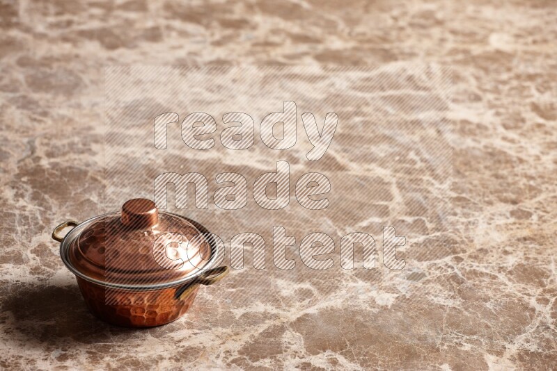 A small copper pot on beige marble background