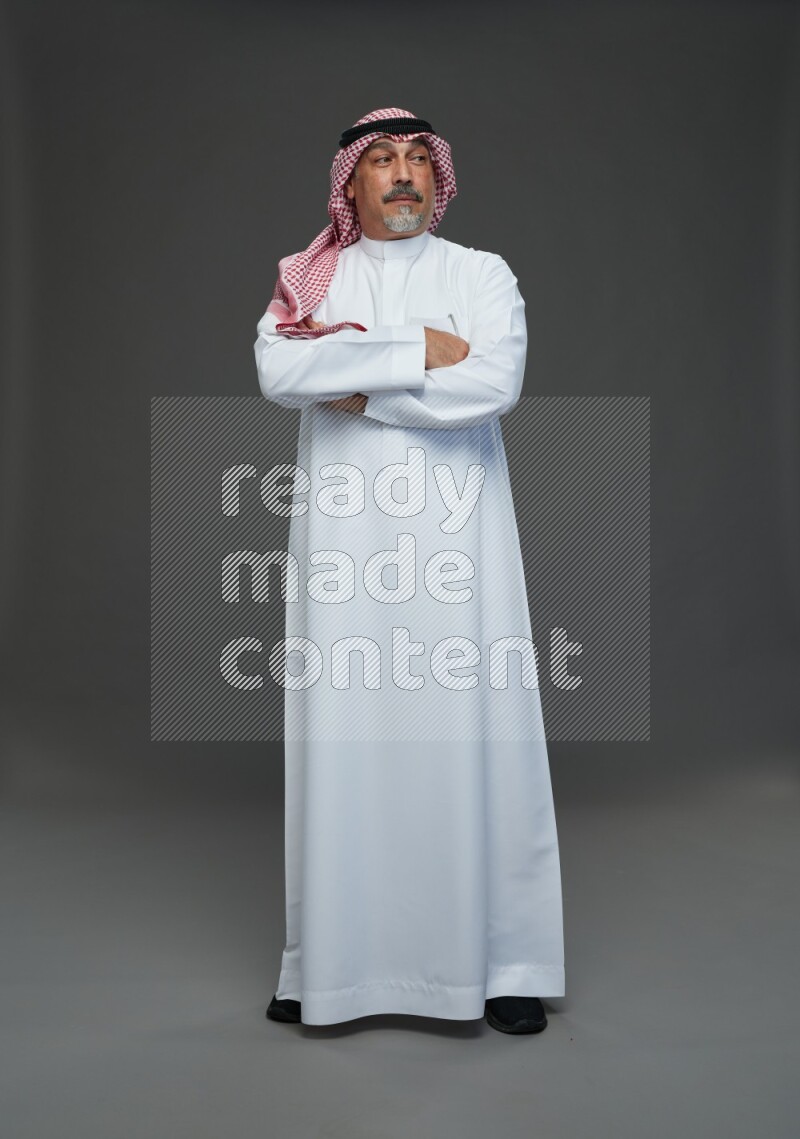 Saudi man with shomag Standing Interacting with the camera on gray background