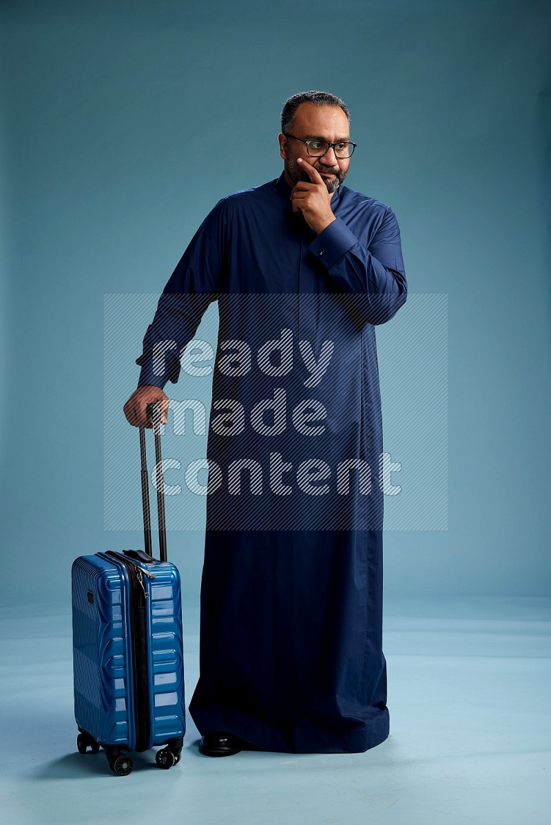 Saudi Man without shimag Standing pulling travel bag on blue background