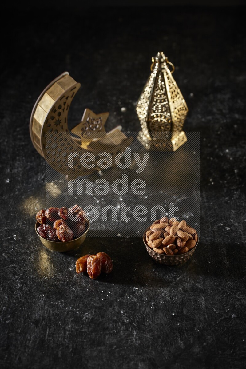 Dates in a metal bowl with almonds beside golden lanterns in a dark setup