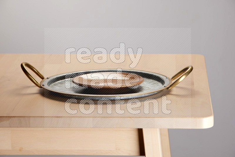 multicolored plate placed on a rounded stainless steel tray with golden handels on the edge of wooden table