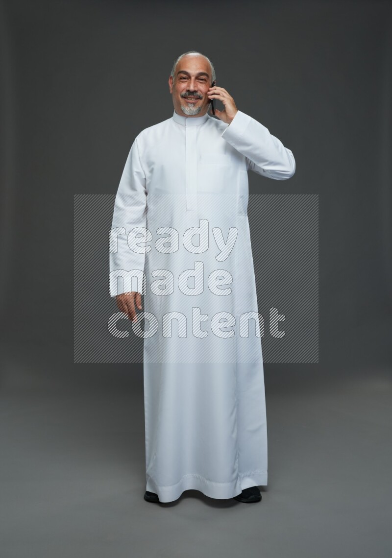 Saudi man without shomag Standing talking on phone on gray background