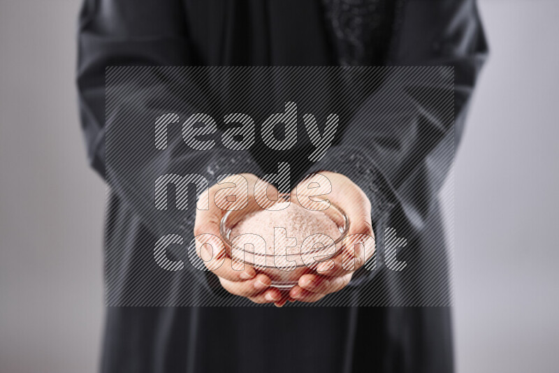Woman in abaya holding different kinds of spices in different positions