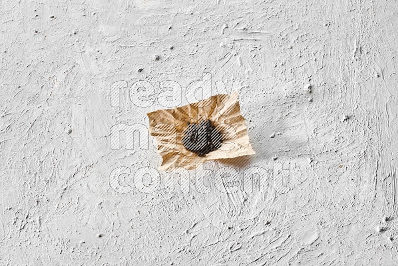 حبوب الفلفل الأسود في قطعة من الورق علي خلفية بيضاء