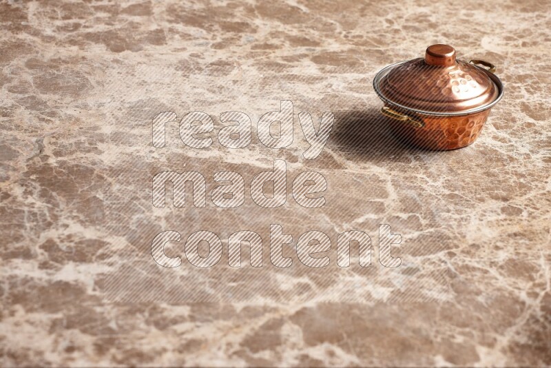 A small copper pot on beige marble background