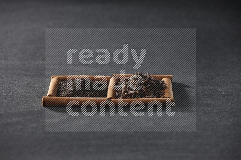 2 squares of cinnamon sticks full of tea and cloves on black flooring