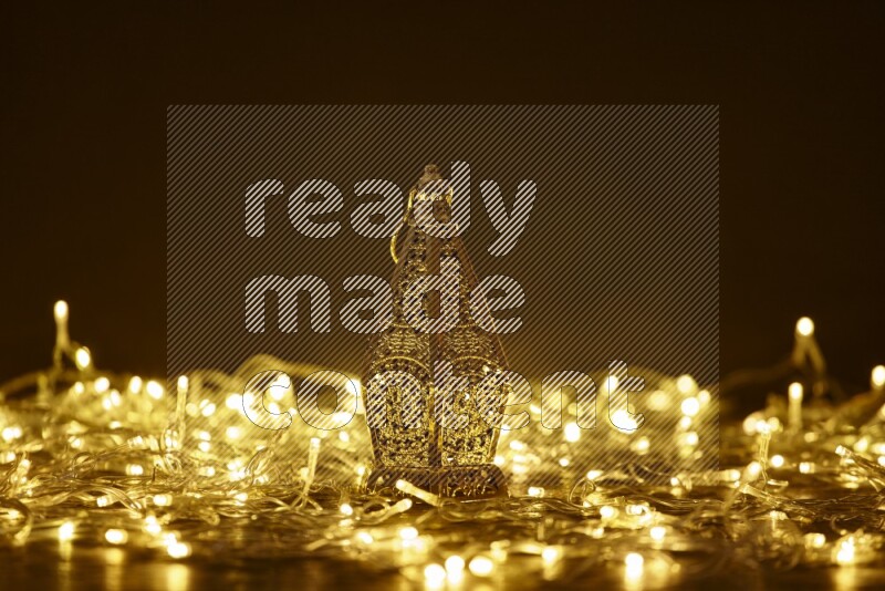 A traditional ramadan lantern surrounded by glowing fairy lights in a dark setup