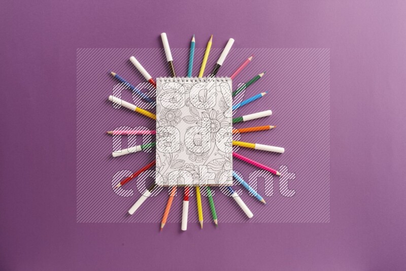 A coloring book with coloring pens on purple background