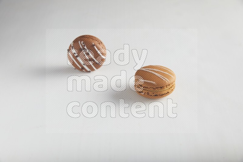 45º Shot of of two assorted Brown Irish Cream, and Brown white Chocolate Caramel macarons on white background