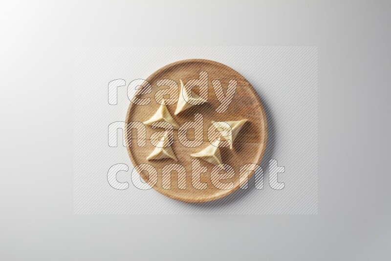 Five Sambosas on a wooden round plate on a white background