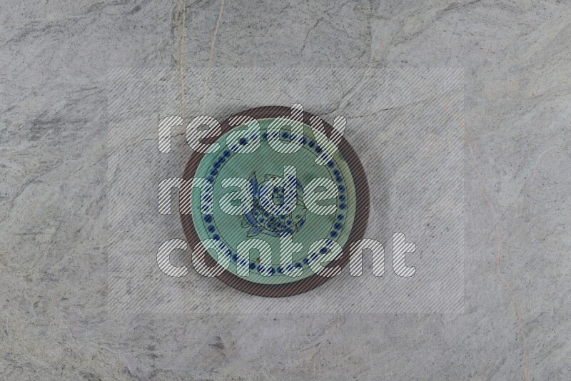A decorative pottery plate on grey marble background