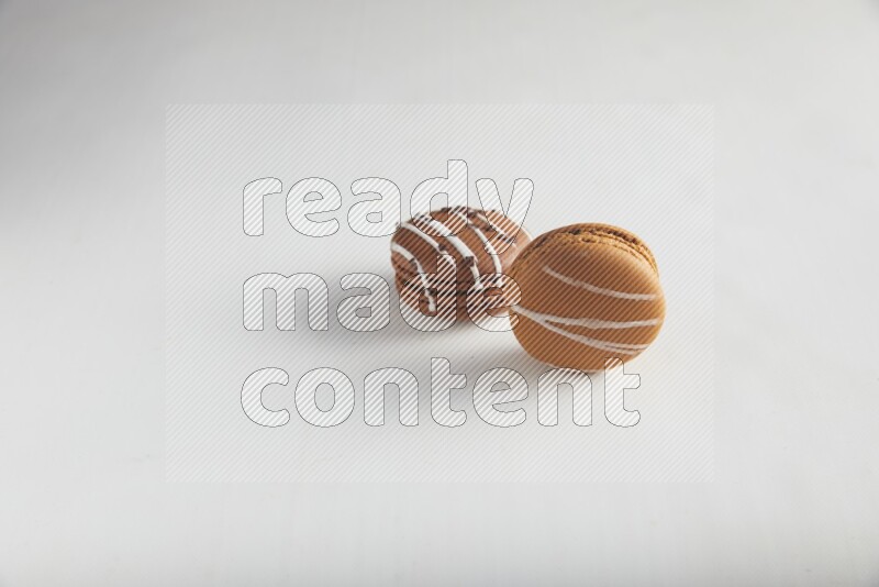 45º Shot of of two assorted Brown Irish Cream, and Brown white Chocolate Caramel macarons on white background