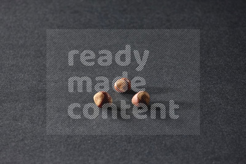 3 hazelnuts on a black background in different angles