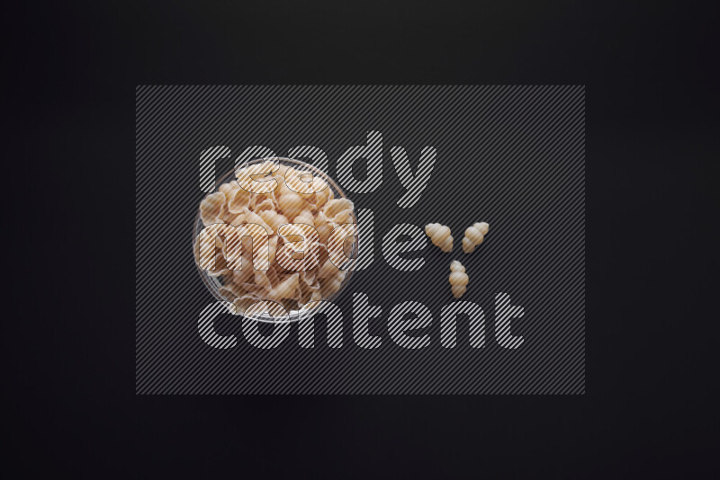 معكرونة قواقع في وعاء زجاجي علي خلفية سوداء