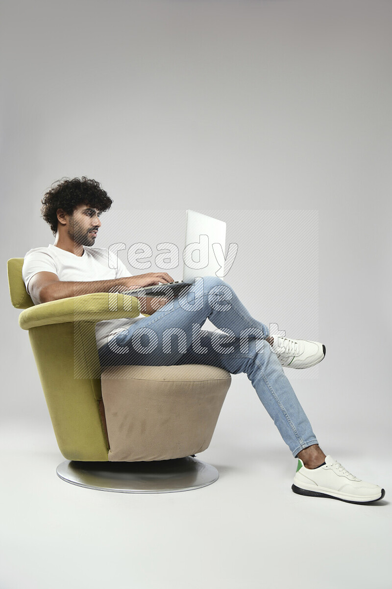 A man wearing casual sitting on a chair working on a laptop on white background