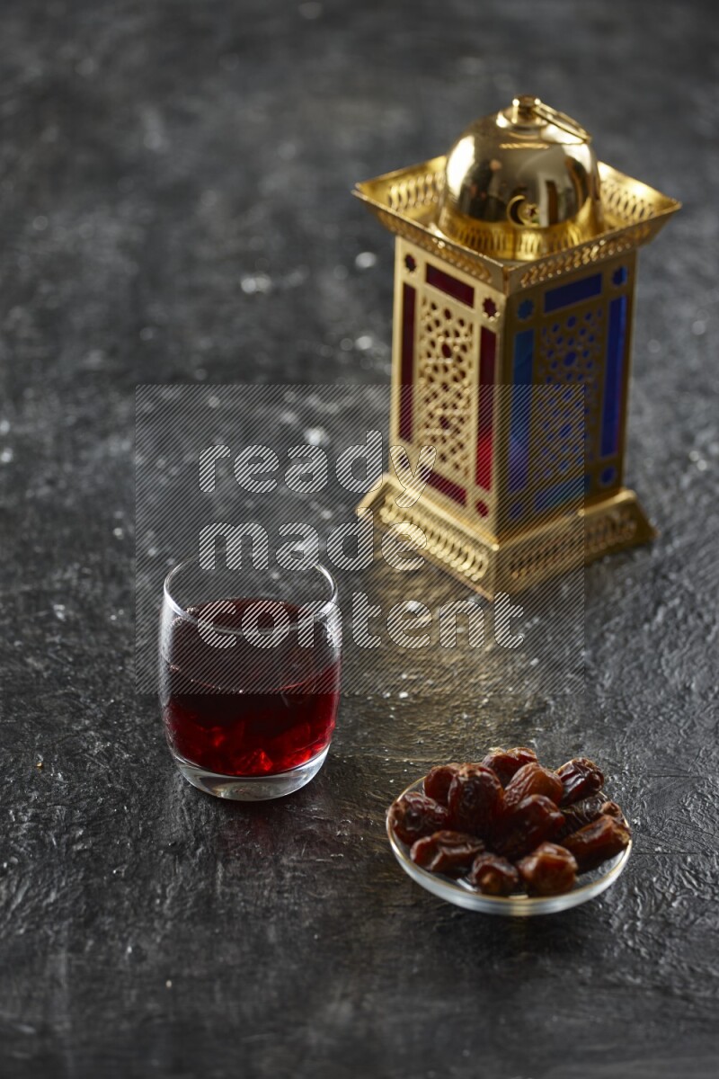 A golden lantern with different drinks, dates, nuts, prayer beads and quran on textured black background
