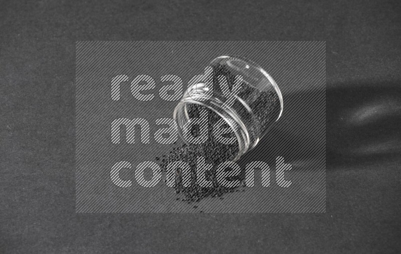 A flipped glass jar full of black seeds and the seeds spread out on a black flooring