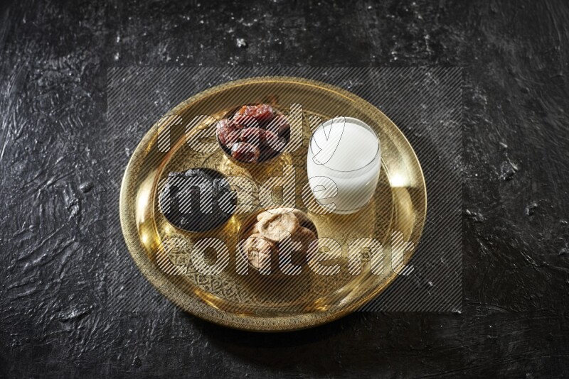 فواكه مجففة في أطباق معدنية مع السوبيا على صينية علي خلفية سوداء