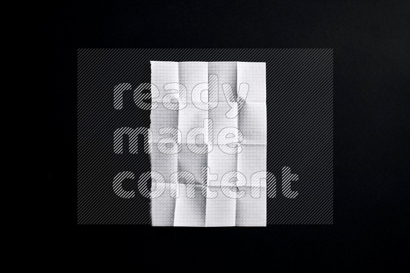 Folded notebook sheet on black background