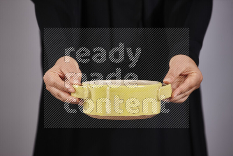 A woman in black abaya holding different pottery essentials in different positions