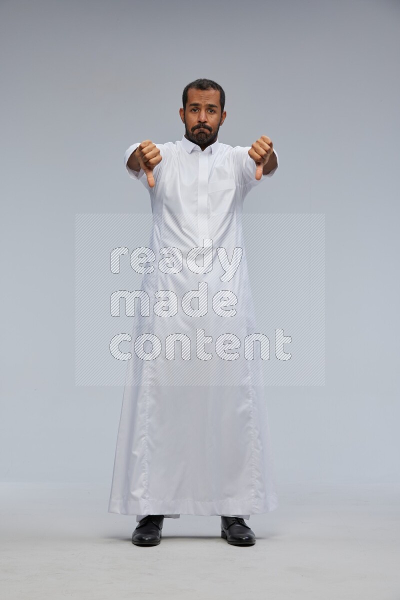 Saudi man Wearing Thob standing interacting with the camera on Gray background