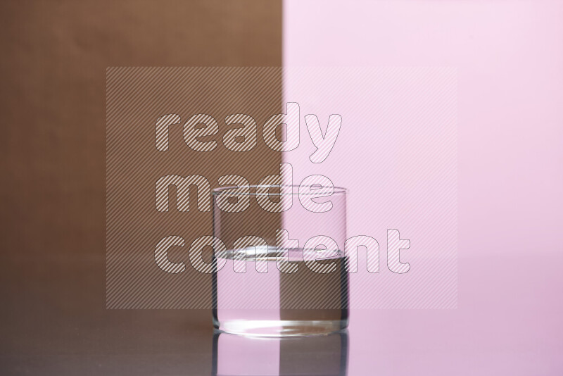 The image features a clear glassware filled with water, set against brown and rose background