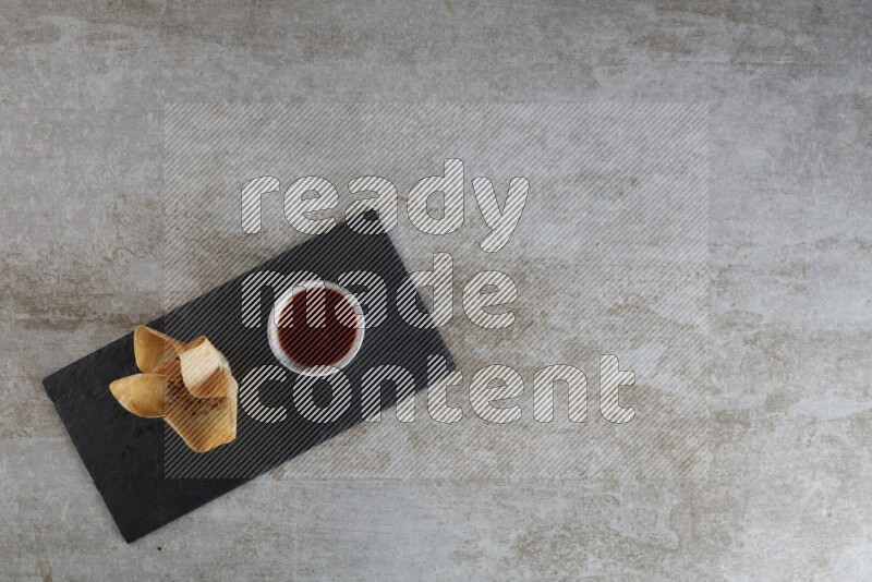 wonton cups with soy sauce ramkin on rectangle slate on grey textured counter top