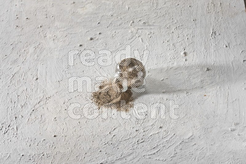 فلفل أسود مطحون في وعاء زجاجي مقلوب علي خلفية بيضاء