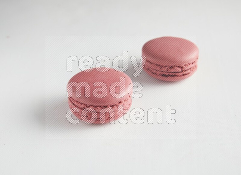 45º Shot of two Pink Raspberry macarons on white background