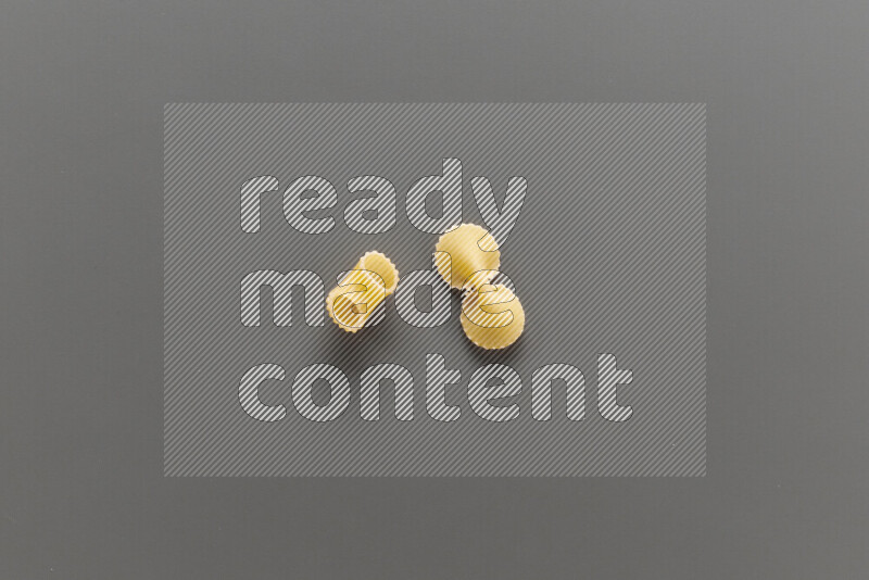 Elbow pasta with other types of pasta on grey background