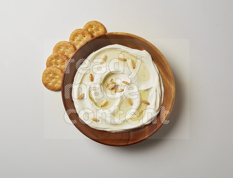 Lebnah garnished with pine nuts in a wooden plate on a white background