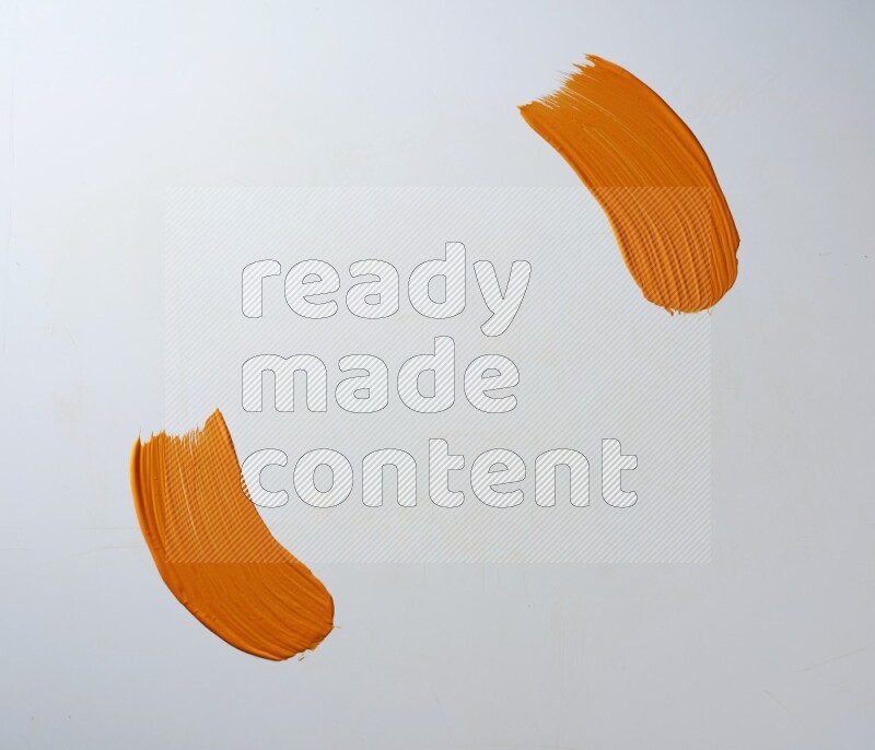 An orange curved painting brush stroke on a white background