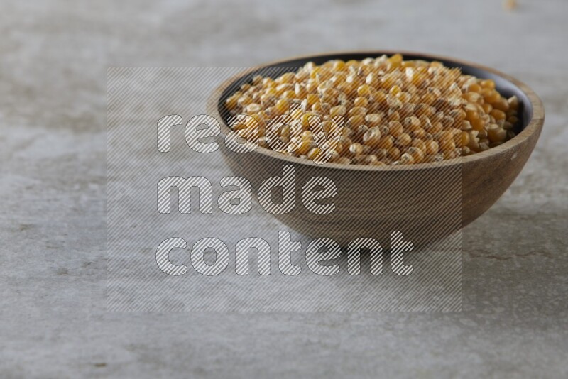 corn kernel in a wooden bowl on a grey textured countertop