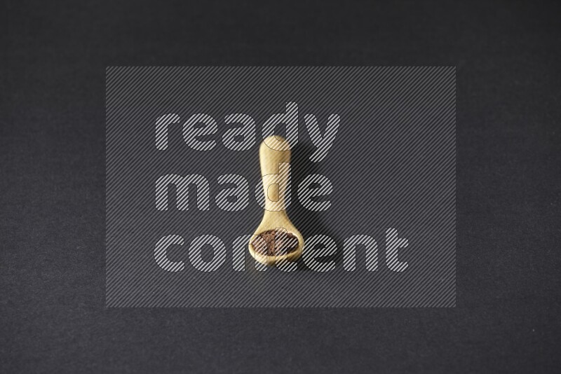 بودرة القرنفل في ملعقة خشبية علي خلفية سوداء