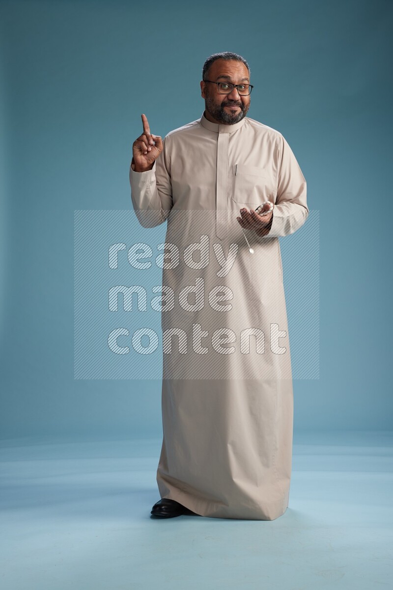 Saudi Man without shimag Standing Interacting with the camera on blue background